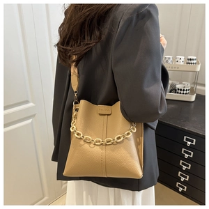 Close-up of beige lychee leather bucket bag with acrylic chain and woven shoulder strap
