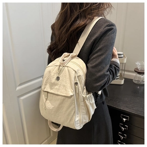 Détail d'un sac à dos en nylon blanc cassé avec poche à rabat et poche latérale