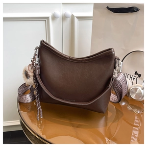 Detail van de bruine leren tas met gedessineerde brede riem en decoratieve tasbedel