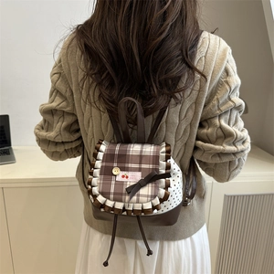 Sac à dos à carreaux avec nœud et bordure en dentelle porté par un mannequin en intérieur
