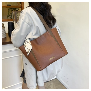 Dettaglio borsa tote in pelle marrone con logo FASHION e foulard in seta sul manico