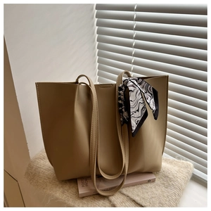 Detail of khaki tote bag with pleated leather texture and ink-patterned silk scarf handle