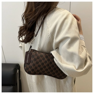 Detailed view of brown letter-pattern underarm bag with metal buckle and leather tag