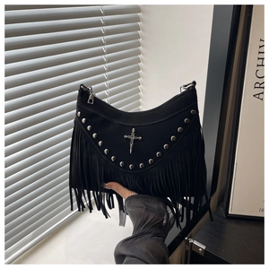 Detail of black punk shoulder bag featuring long tassels, silver rivets, and cross charm