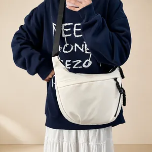 Detail van witte halfronde crossbodytas van nylon met een geknoopte ritstrekker