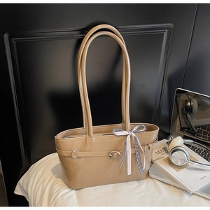 Detail of khaki leather shoulder bag with a black and white checkered bow and metal buckle