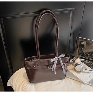 Detailed view of dark brown tote bag with belt buckle and decorative plaid ribbon bow