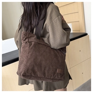 Detalle de bolso tote de pana marrón oscuro que muestra textura gruesa y etiqueta de cuero