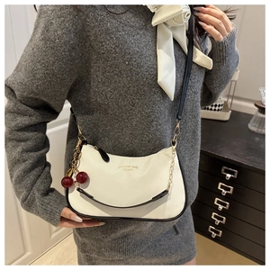 Dettaglio borsa in pelle bianca con grana litchi con ciondolo a ciliegia e catena