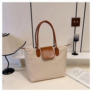 Gros plan du sac cabas en nylon crème avec rabat en cuir brun et bouton pression doré