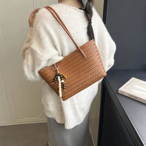 Brown woven tote bag with long leather straps and beaded tassel charm for women
