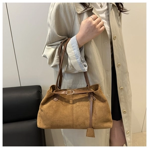 Detailed texture of brown suede tote bag with slim shoulder straps and metal buckle
