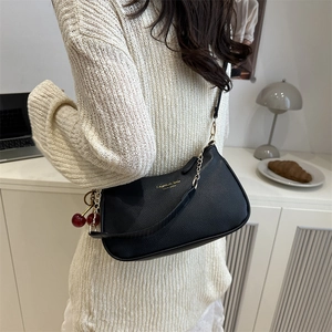 Elegante borsa sottobraccio in pelle nera con catena dorata e ciondolo a ciliegia