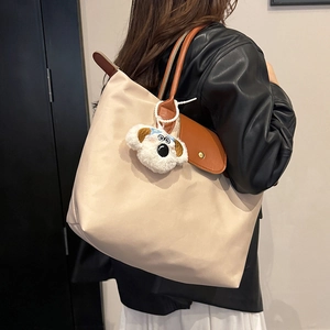 Sac fourre-tout en nylon beige avec anses en cuir marron et breloque chien sur l'épaule