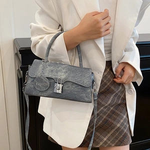 Piccola borsa retrò grigio chiaro con chiusura argento indossata da modella in bianco