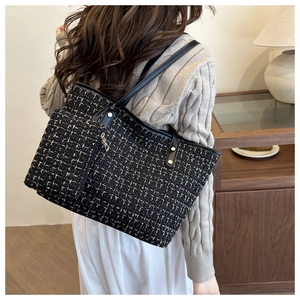 Detail of tweed shoulder tote bag with black and gold woven texture and mini charm pouch