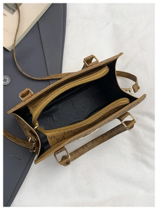 Detailed interior of a brown letter-print handbag with zipper pockets and strap