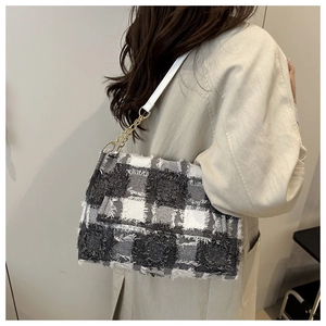 Detail of tweed checkered bag featuring fringe texture and golden metal chain strap