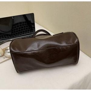 Close-up of a dark brown retro cylindrical tote bag with polished oil wax leather texture