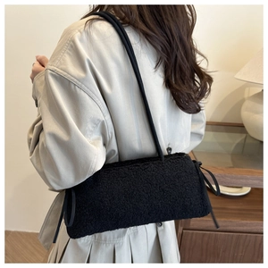 Détail du sac à bandoulière noir en peluche avec nœuds décoratifs et texture douce