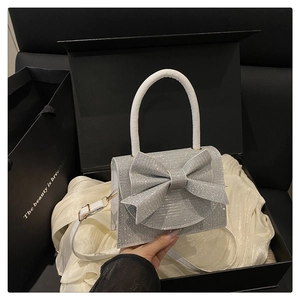 Dettaglio della borsa glitterata argento con grande fiocco e manico bianco elegante