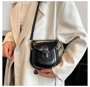 Chic black crossbody phone bag in premium leather finish worn over a white blazer jacket