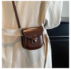 Detail view of dark coffee glossy leather horseshoe bag with polished silver hardware