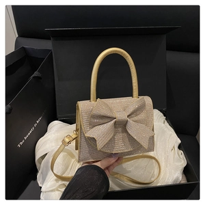 Dettaglio borsa a mano con strass oro champagne e fiocco in una confezione regalo di lusso