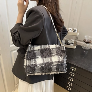 Elegant plaid crossbody bag with chain strap and fringe detail shown on a model