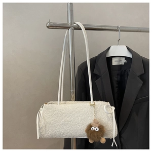 Détail du sac fourre-tout blanc en peluche avec nœuds tissés et breloque monstre