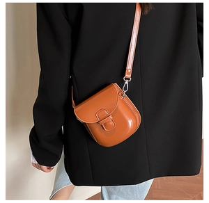 Close-up of a brown leather crossbody bag with a flap closure and adjustable strap