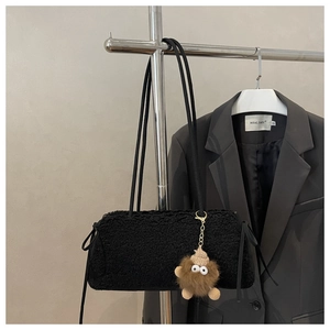 Détail d'un sac cabas en peluche noire orné d'un adorable charme de dessin animé marron
