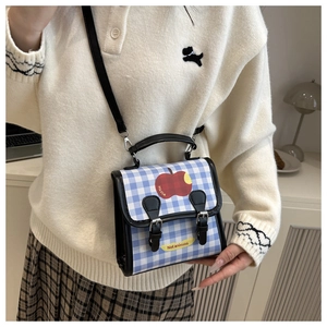 Detail view of plaid crossbody bag with apple print, dual buckles and adjustable black strap
