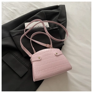 Detailed macro view of pink crocodile textured bag with gold studs and slim handle