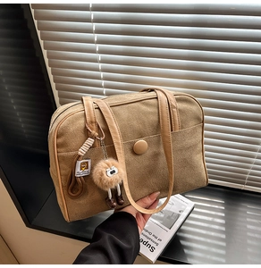 Detail of khaki suede tote bag featuring brown leather handles and plush eye charm