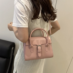 Pink minimalist crossbody bag with top handle and silver buckle shown on a model