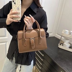 Minimalist brown matte leather square handbag with silver horseshoe buckle on a model