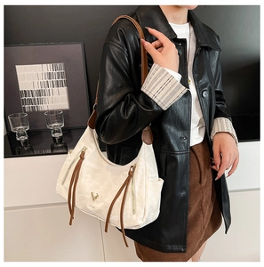 Détail du sac à bandoulière blanc avec glands en cuir marron et logo cerf doré