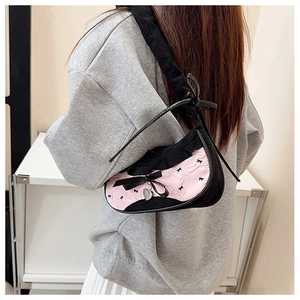 Detail view of pink and black bow shoulder bag with silver heart pendant on a model