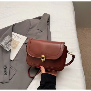 Detail of reddish-brown leather flap bag with vintage golden circular buckle and strap
