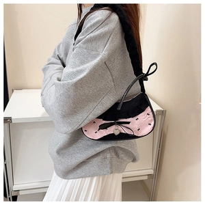 Detail of pink ruffled shoulder bag with black lace trim and silver heart pendant