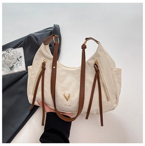 Détail du sac en tissu blanc avec poignées marron et emblème logo tête de cerf doré