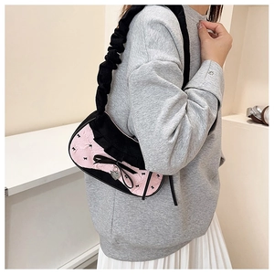 Close-up of pink textured handbag with black ruffle trim, bow detail and heart charm