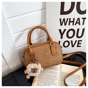 Détail d'un sac Boston marron mat avec une jolie peluche de mouton et des poignées souples