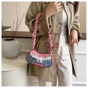 Detail of denim and red gingham patchwork bag with lace trim and cherry charms