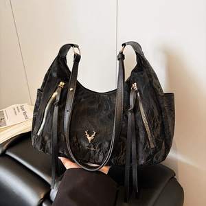 Détail du sac cabas plissé noir avec logo cerf doré et longues lanières en cuir