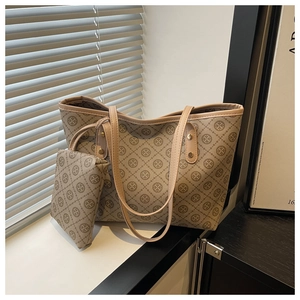 Detailed view of brown monogram tote bag set with matching zippered clutch in sunlight