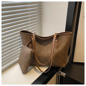 Detail view of brown monogram tote bag set and small pouch on minimalist window background