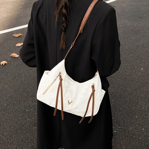 Sac à bandoulière blanc en demi-lune avec lanière marron et logo cerf porté par mannequin