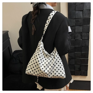 Vue détaillée du grand sac cabas blanc à pois noirs avec une large bandoulière souple